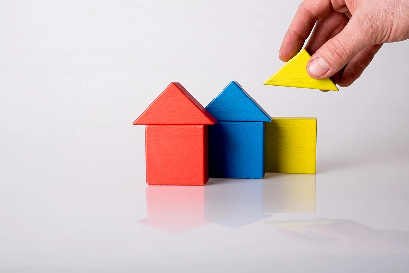 Symbolbild für den Basismodulbaukasten: Aus Bauklötzen werden drei Häuser gebaut.